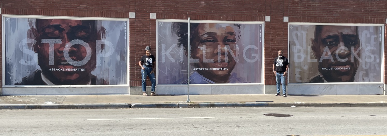 A person standing in front of a building with a poster on the side.