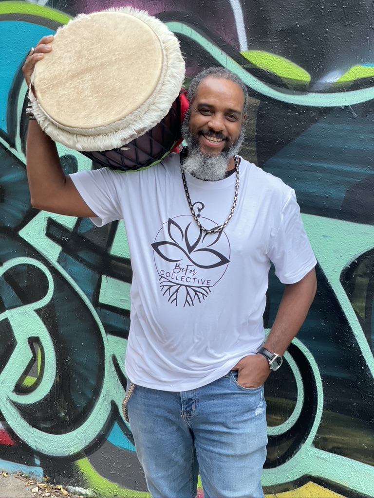 A man holding a drum in front of a wall.