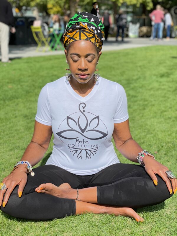 A woman sitting in the grass doing yoga.