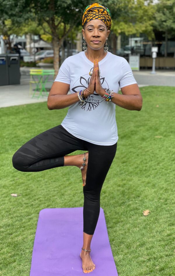 A woman in black pants and white shirt doing yoga.